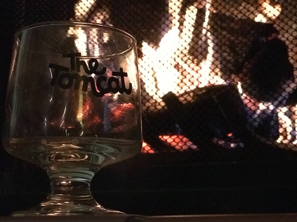 Small stemmed glass on the left foreground with a roaring fire behind